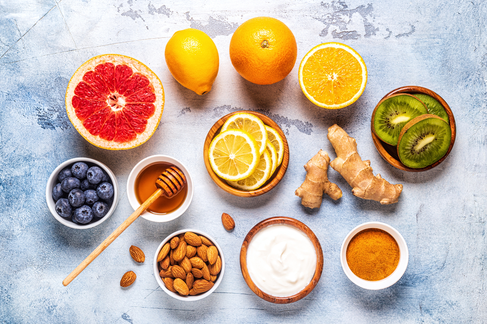 Flat lay of different immune system-boosting foods, such as oranges, ginger and honey.