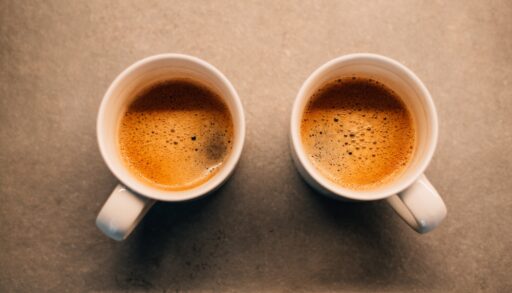 Overhead view of two white mugs filled with coffee.