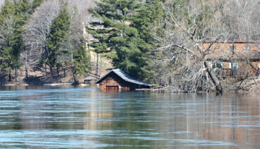 Wooden cottage partially submerged in water during spring flooding in Huntsville, Ontario in 2013.