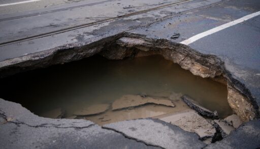 Close-up of a large sinkhole in a road.