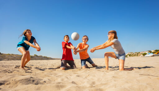 Family playing volleyball on the beach.
