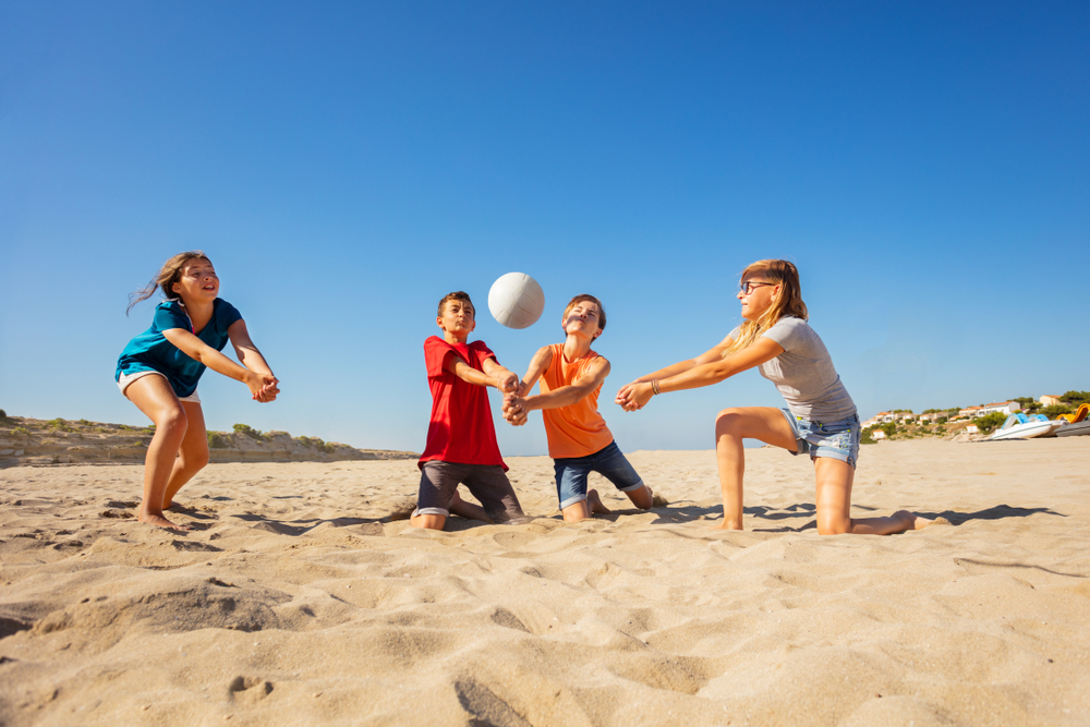 Family playing volleyball on the beach.