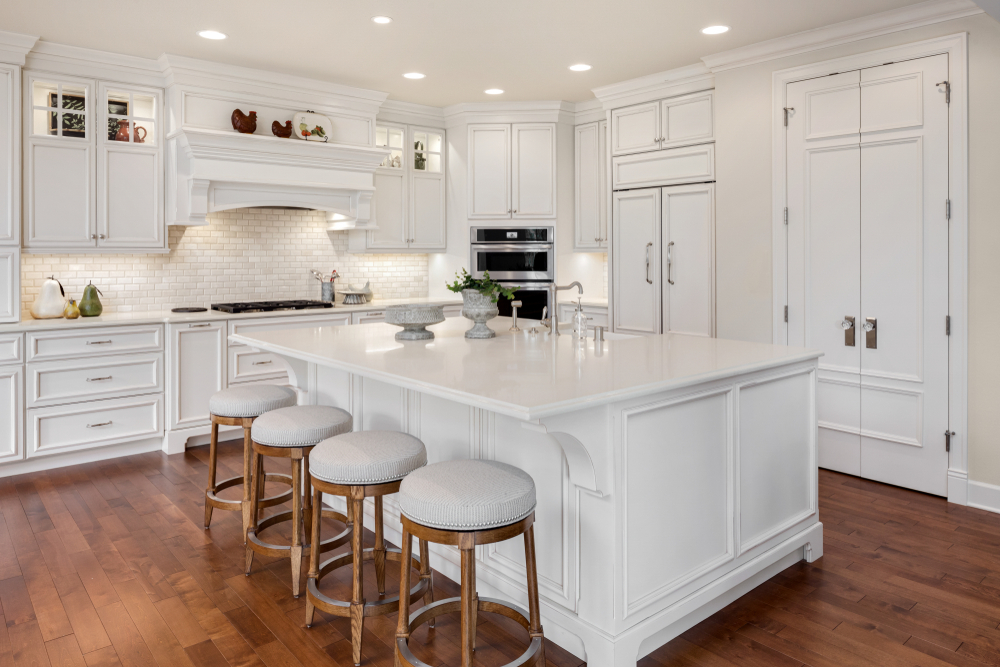 Modern, white kitchen with dark-coloured wooden floors.