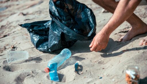 Close-up of a person picking up trash on a beach.