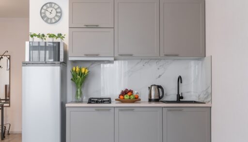 Small, modern kitchen with grey cabinets and small appliances.