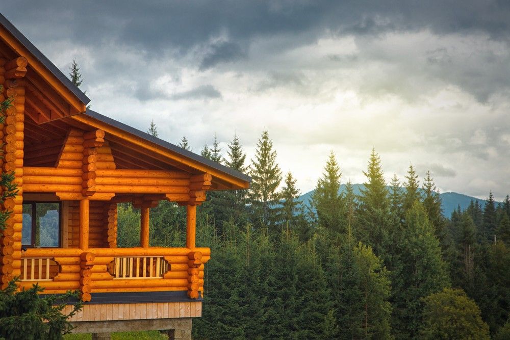 Log cabin overlooking a forest with a mountain in the background.