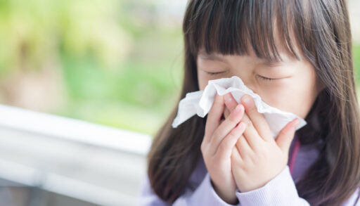 Close-up of a little girl blowing her nose.