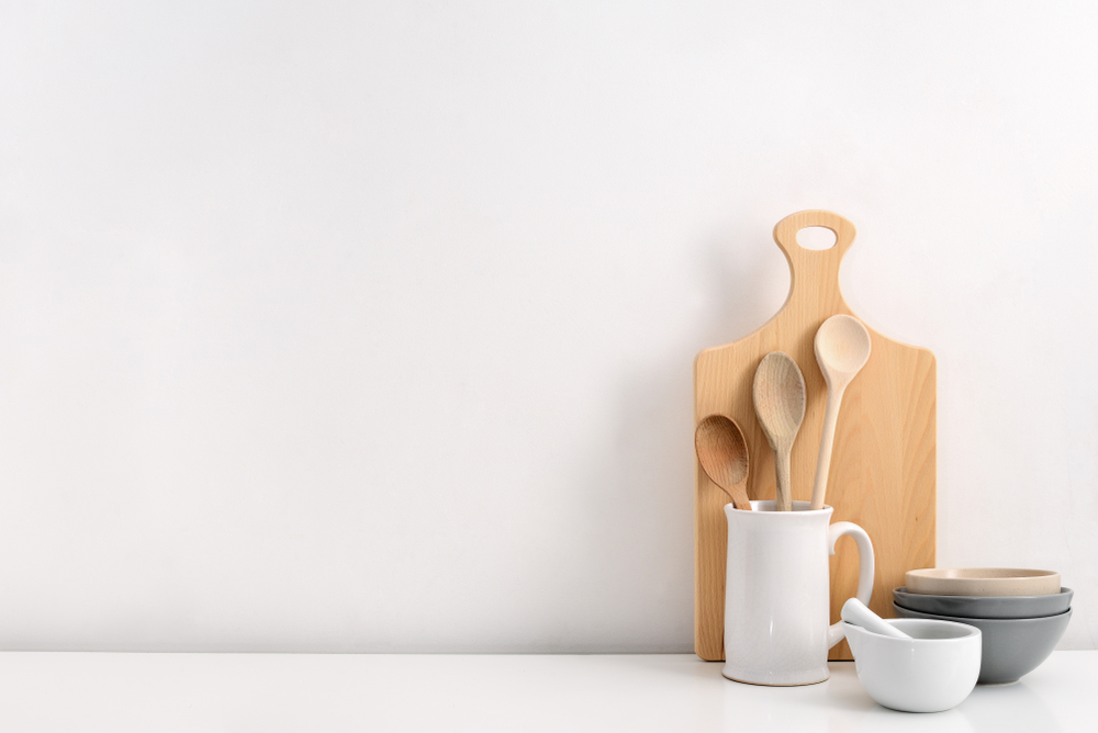 Wooden cutting board with a jar of kitchen utensils and bowls.