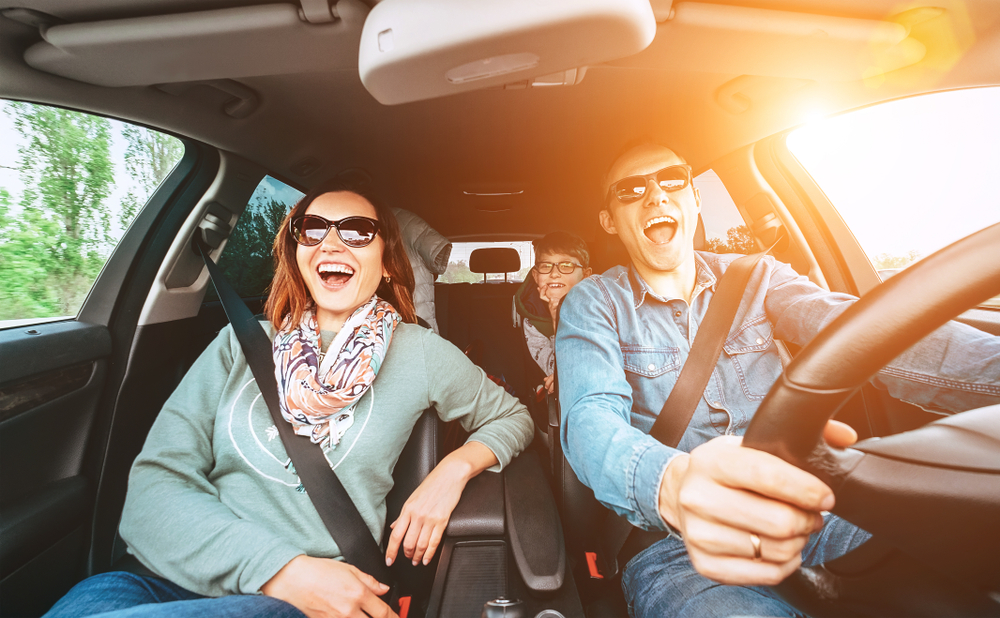 Young family driving in a car, smiling and singing.