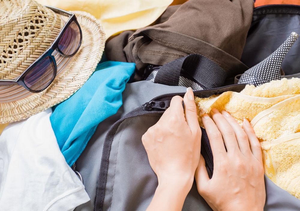 Close-up of a woman's hands packing a suitcase.