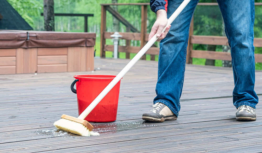 View of a man's feet and a broom and bucket as he washes his deck.
