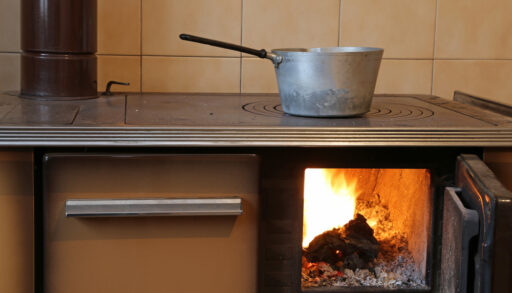 Close-up of an old, wood-burning stove with a pot on top.