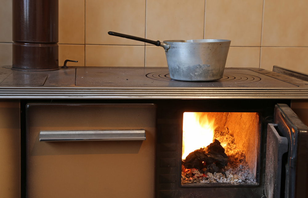 Close-up of an old, wood-burning stove with a pot on top.