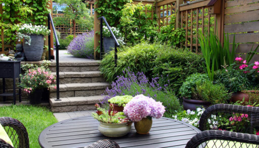 Small garden with patio furniture and pink flowers.