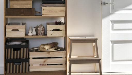 Wooden storage shelves and crates next to a wooden step-stool and white doorway.