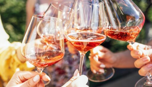 Group of people toasting with glasses of rose wine.