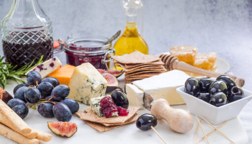 Snack platter with different types of cheese, fruit and crackers.