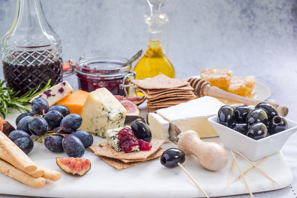 Snack platter with different types of cheese, fruit and crackers.