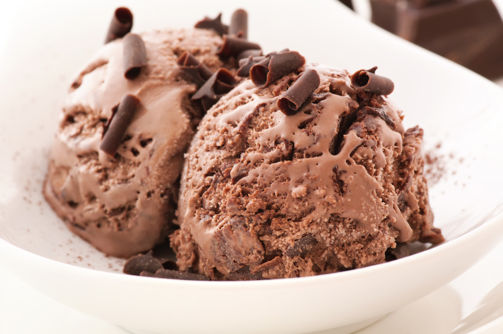 Close-up of two scoops of chocolate ice cream toped with chocolate curls.