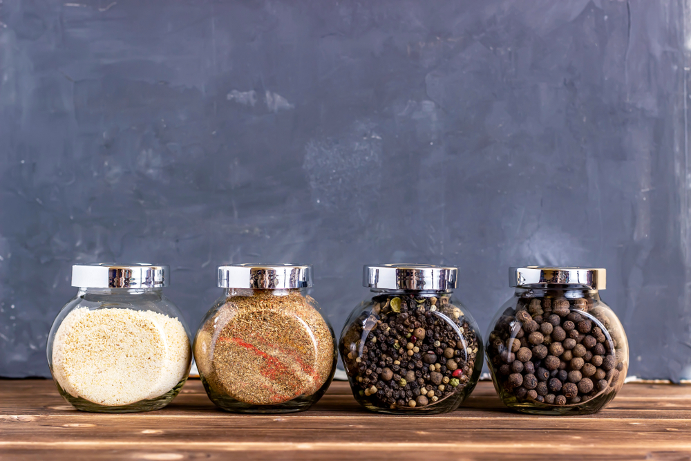 Four small, glass containers with different spices inside.
