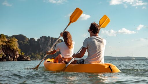 Young couple paddling on a lake in a yellow kayak.