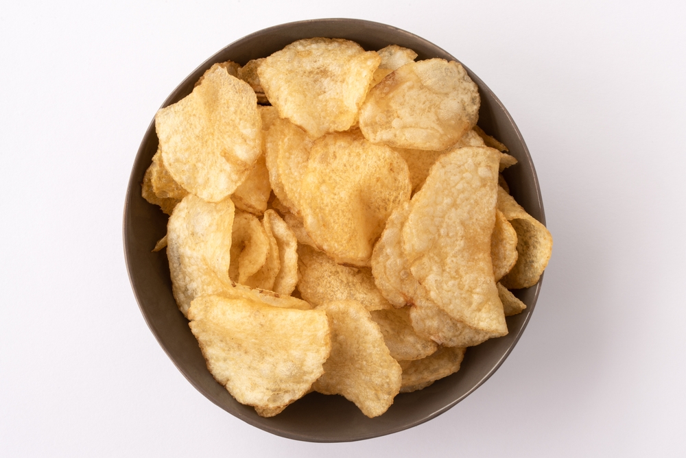 Overhead view of plain potato chips in a brown bowl.