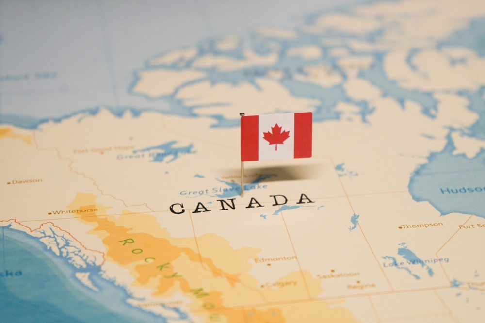 Close-up of a small Canadian flag on a map of Canada.