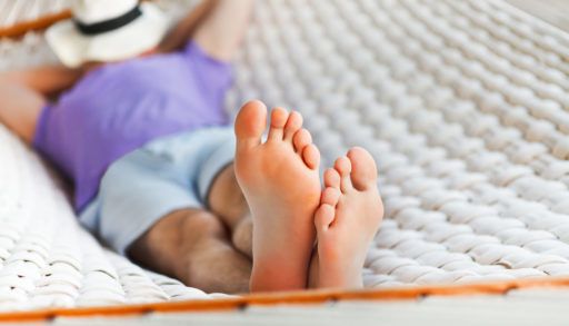 Close-up of a man's feet as he lays on a hammock, napping.
