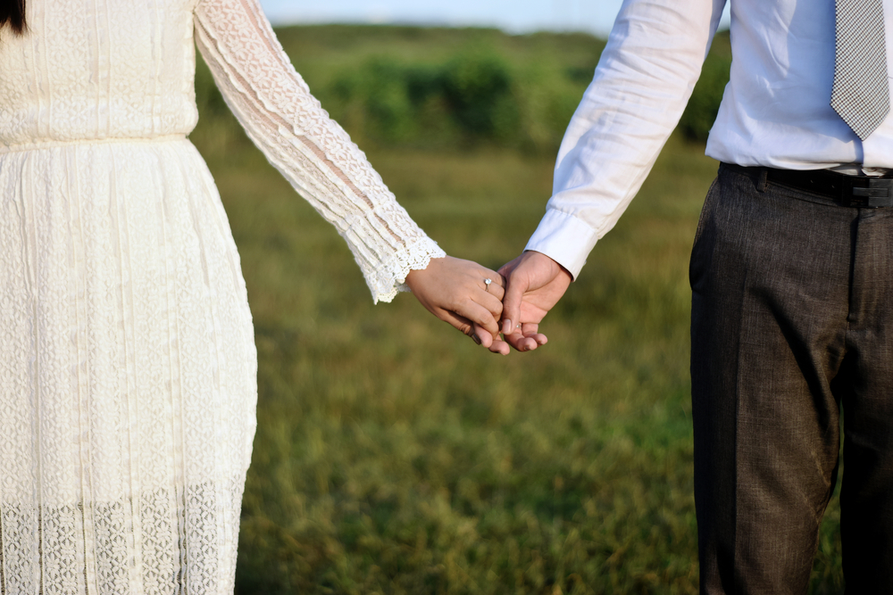Close-up of a married couple holding hands.