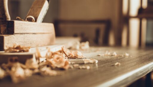 Wood blocks and shavings stacked on a wooden table in a workshop.