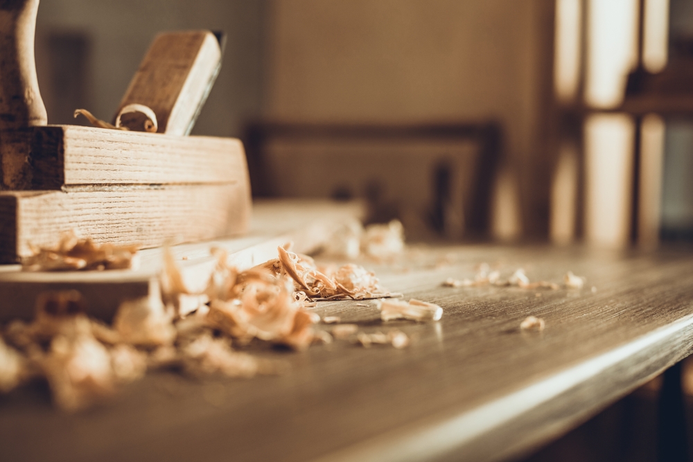 Wood blocks and shavings stacked on a wooden table in a workshop.