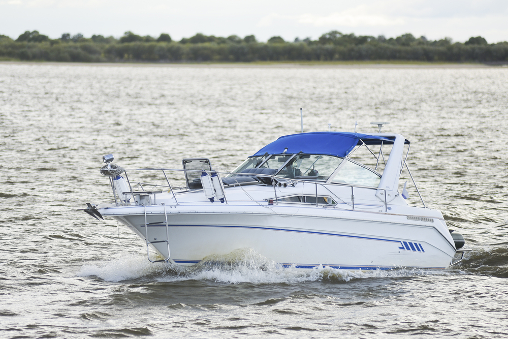A white and blue yacht speeding across a lake.