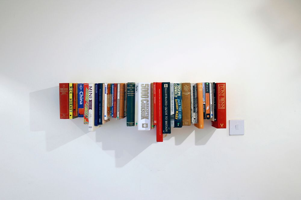 Books hanging from wall with upper edges aligned