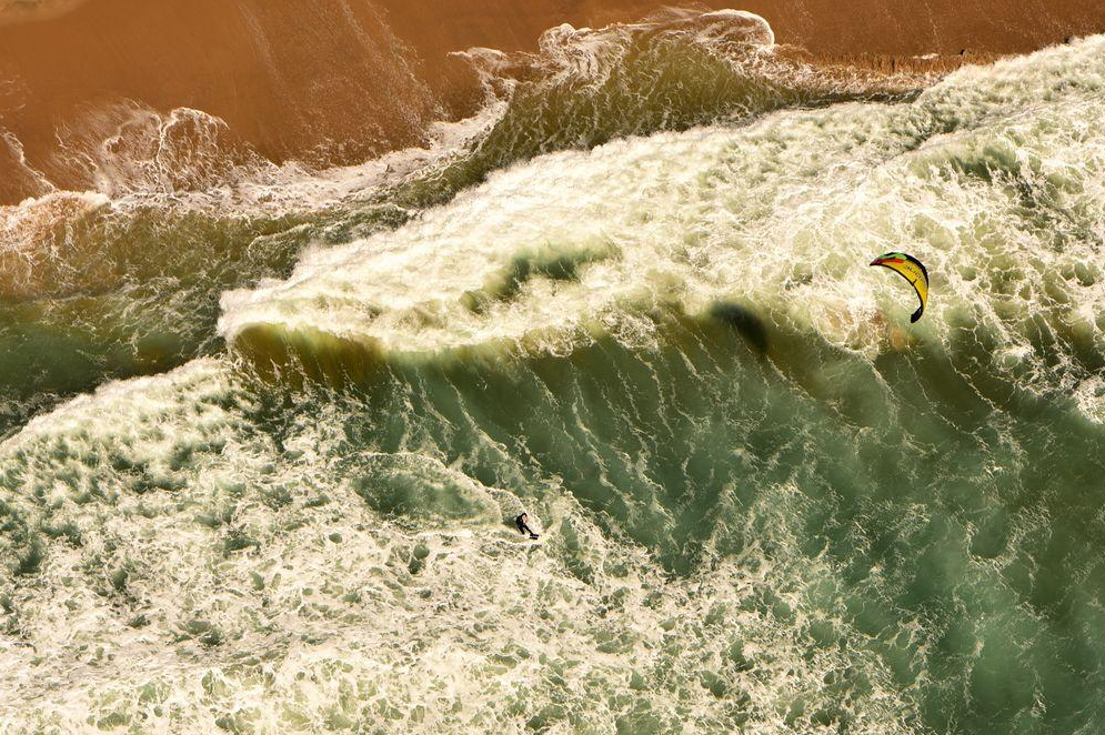 aerial photo of the beach and a windsurfer