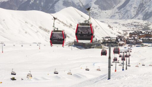 Red ski gondola going up a snow covered ski hill.