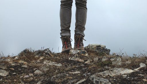 Person's legs in hiking boots standing on hiking trail
