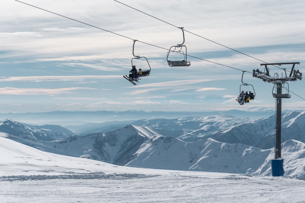 Skiers and snowboarders riding chair lift at a winter resort.