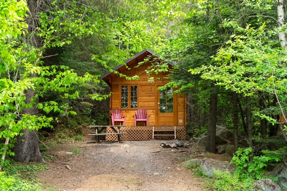 A small wooden cottage surrounded by green trees.