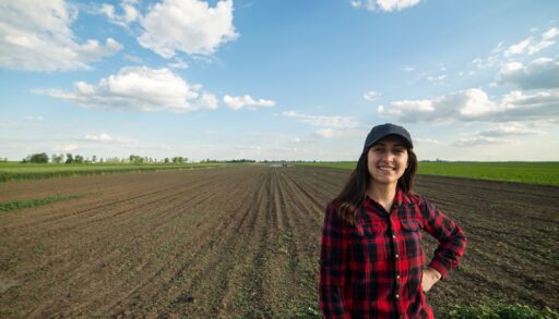 Farmer in red plaid shirt standing in a field.