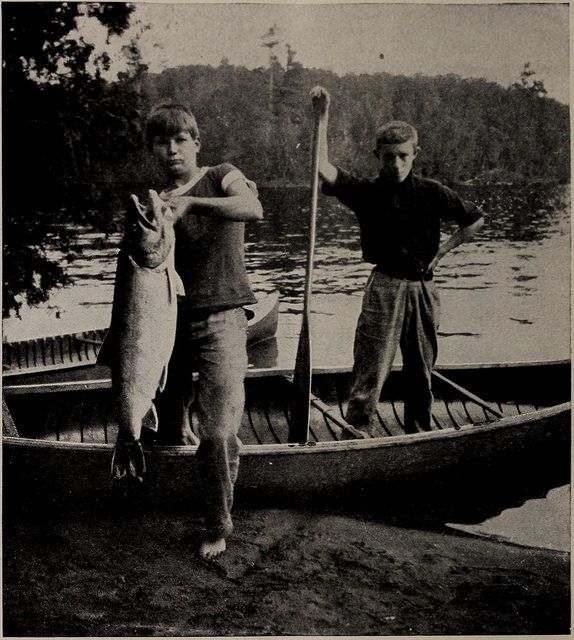 Black and white photos of boys in canoe with a fish