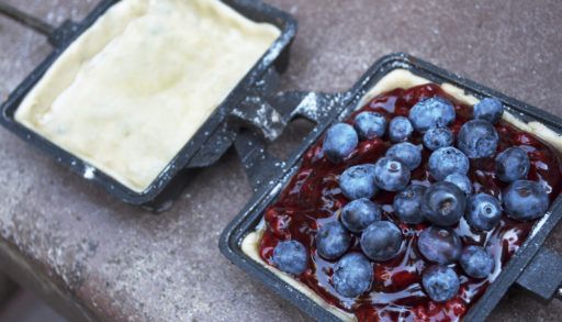 Uncooked pie dough with a blueberry filling in a jaffle iron.
