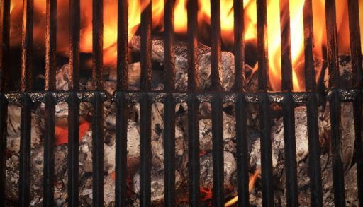 Top view of an empty, clean barbecue with charcoal burning underneath.
