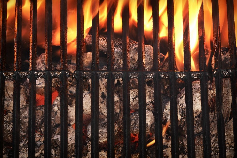Top view of an empty, clean barbecue with charcoal burning underneath.