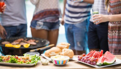 A group of people standing around a table with food.