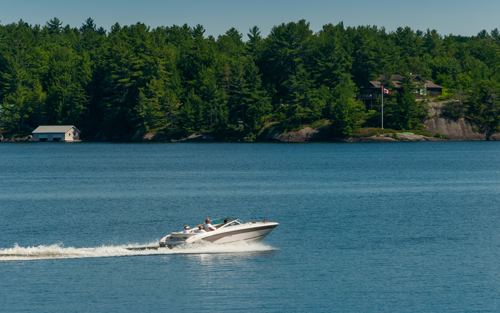 A white motor boat speeding across Lake Muskoka, Ontario.