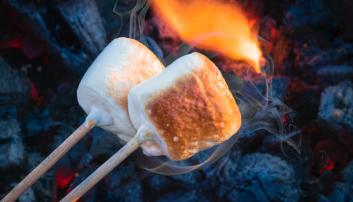 Close-up of two marshmallows being roasted over a campfire.