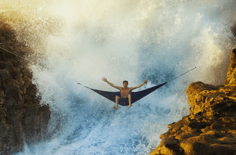 a man in a hammock above a large waterfall