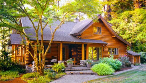 A modern log cabin surrounded by trees.