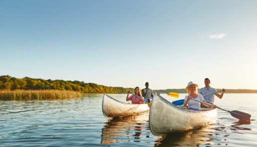 Two canoes each with two people in them on a lake.