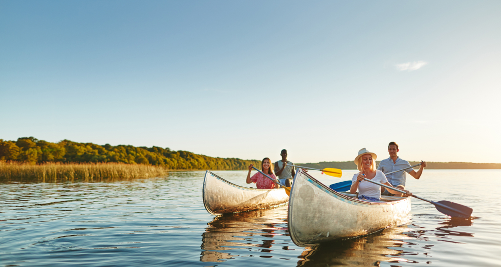 Two canoes each with two people in them on a lake.